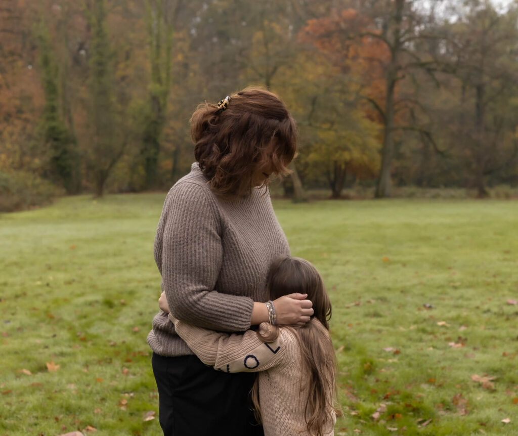 Familienfotografin Dülmen & Umgebung, Mama & Me Shooting Outdoor, die Tochter umarmt ihre Mama & schaut nicht zur Kamera. Die Mama schaut währenddessen liebevoll hinunter