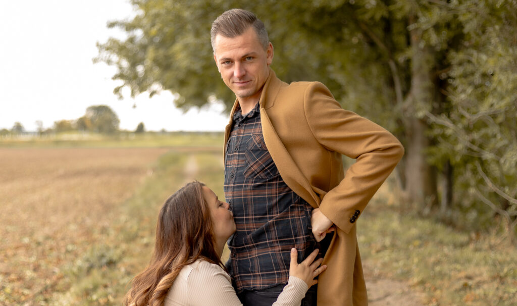 Schwangere Frau küsst Mann auf Bauch