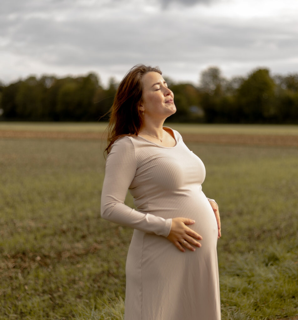 Schwangere Frau genießt die Schwangerschaft & die Sonne auf ihrer Haut