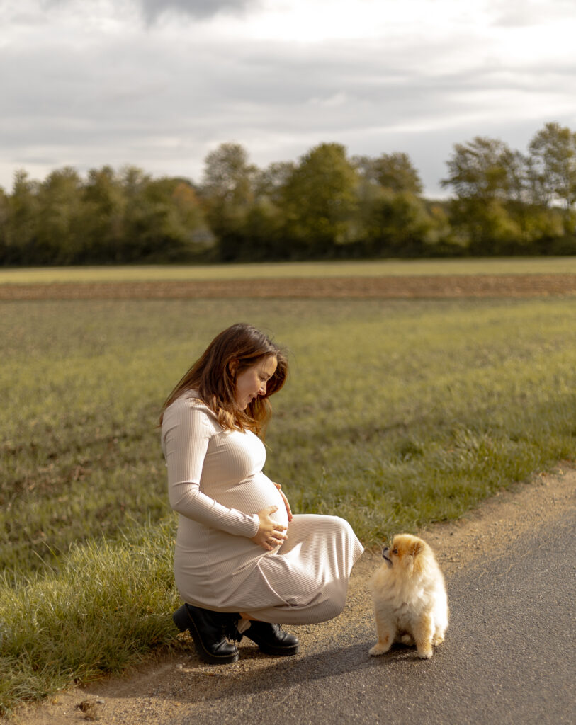 Schwangere Frau hockt vor ihrem Hund