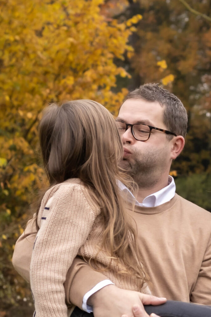Papa hält seine Tochter auf dem Arm & machen gemeinsam dicke Backen