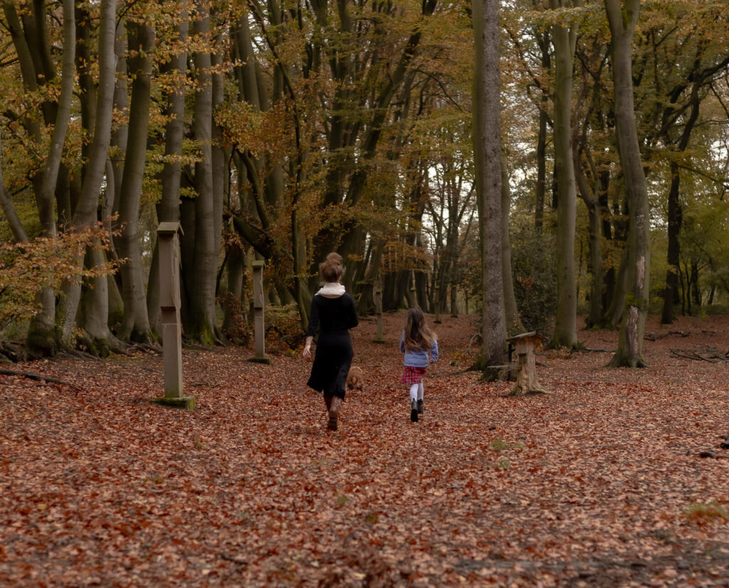 Mama & Tochter & Hund laufen im Wald von der Kamera weg