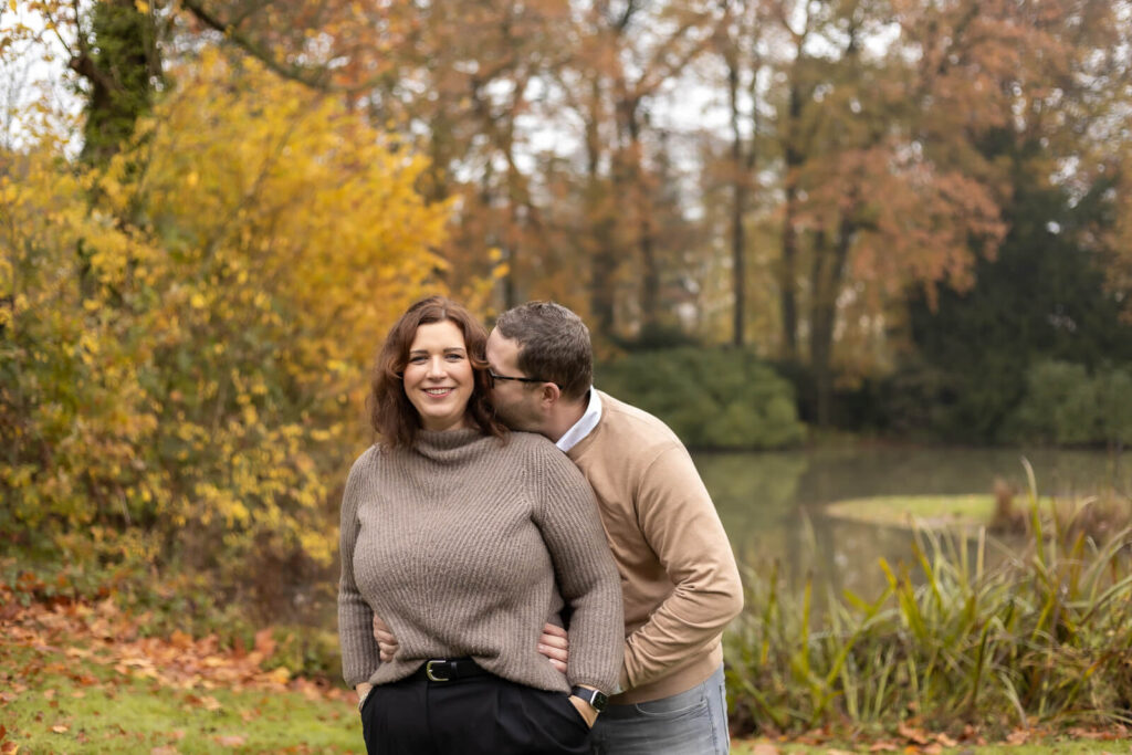 Mann hält seine Frau von hinten fest & flüstert ihr liebevoll ins Ohr
