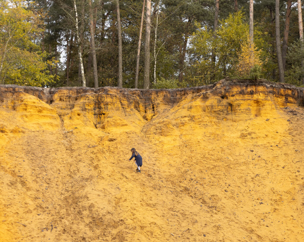 Tochter klettert an der Sandkuhle hoch