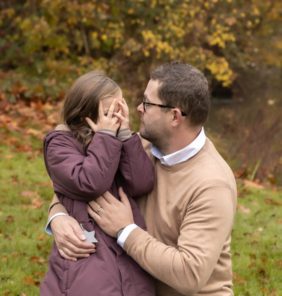 Tochter sitzt auf dem Bein ihres hockenden Papas