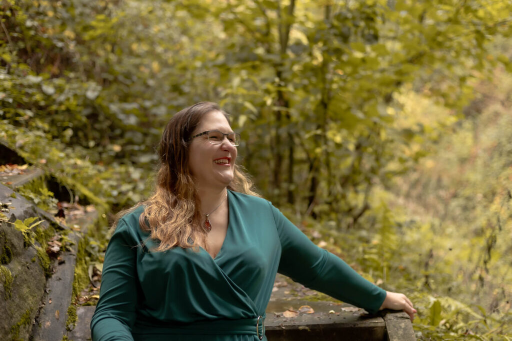 Frau sitzt auf Treppe & schaut lachend von der Kamera weg