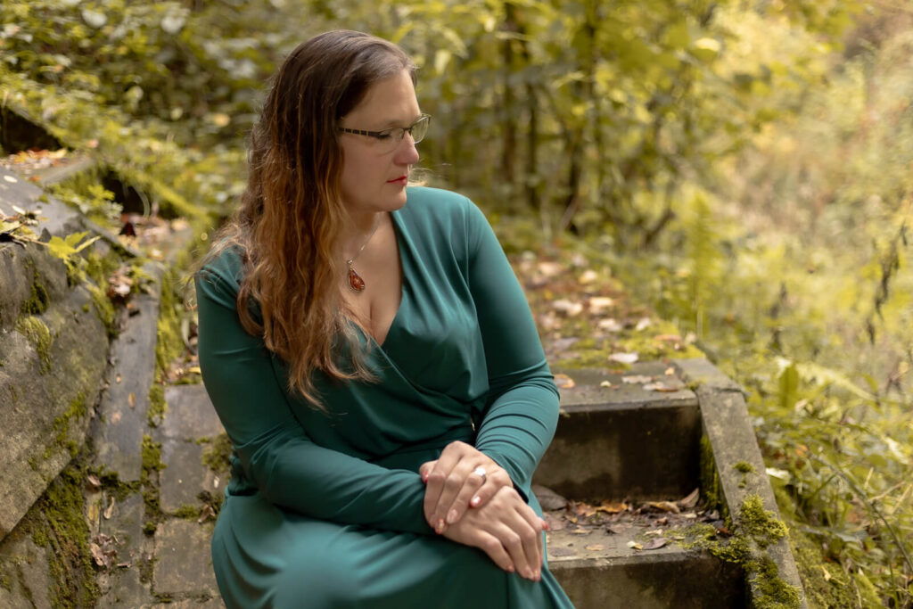 Frau sitzt auf Treppe & schaut nachdenklich von der Kamera weg